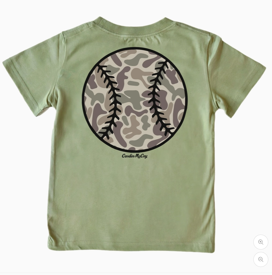 A sage green short-sleeve t-shirt shown from the back, featuring a large circular baseball graphic with a camouflage pattern and black stitching details, with the brand name