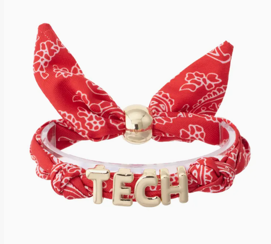 A red bandana-patterned bracelet featuring a bow, a clear acrylic band, and a gold-tone 'TECH' letter charm on a white background.