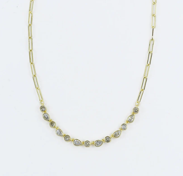 A gold paperclip chain necklace featuring a row of small teardrop-shaped clear gemstones in gold settings, displayed against a plain white background.