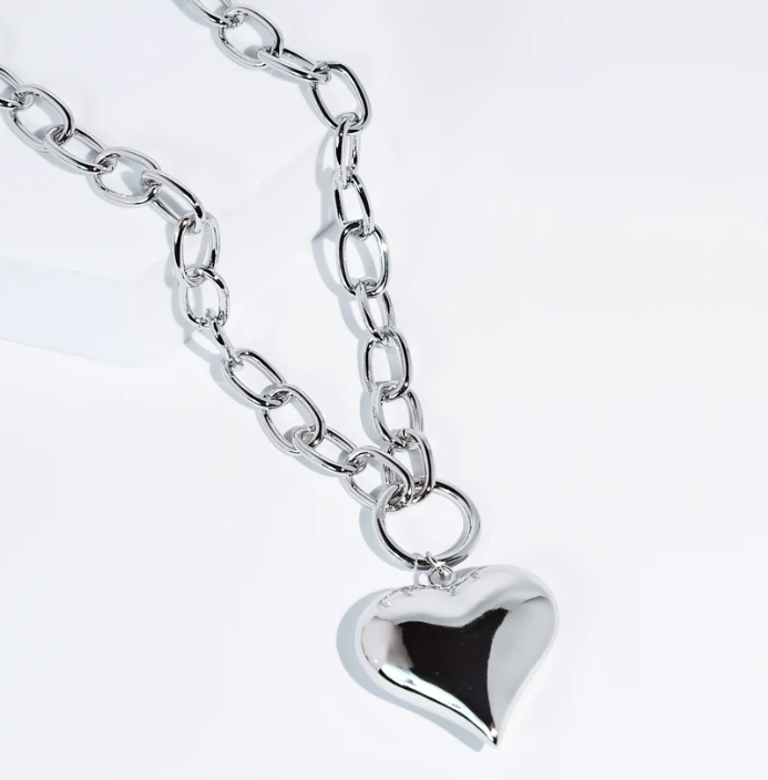 A polished silver heart-shaped pendant necklace on a matching silver link chain, photographed on a clean white background.