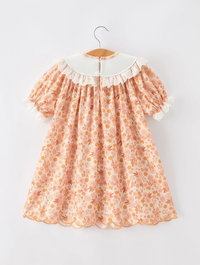 Floral dress on a hanger against a white background back view