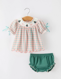 A toddler girl's two-piece outfit set consisting of a short-sleeve plaid blouse on a wooden hanger and matching ruffled bloomers, displayed against a clean white background.