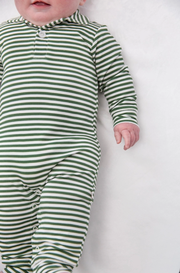 A close-up of a baby wearing a green and white striped long-sleeve footless sleeper with a buttoned collar, lying on a white background.