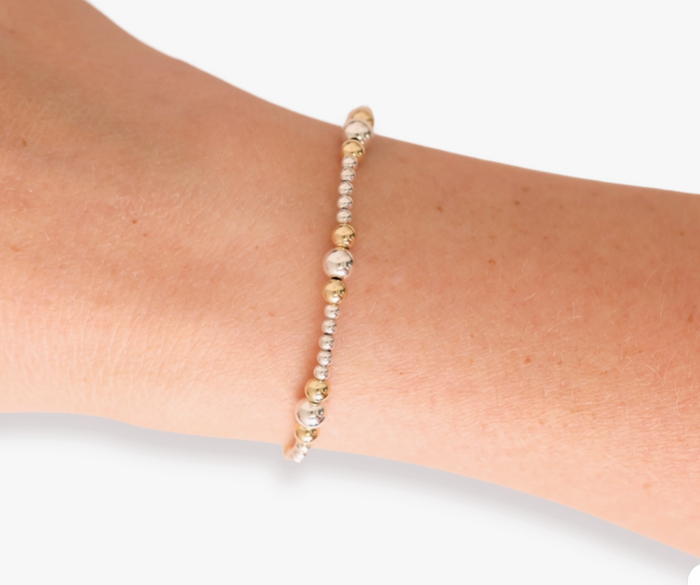 Bracelet with gold and silver beads on a wrist against a white background