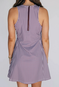 Back view of a person wearing a sleeveless checkered dress on a plain background