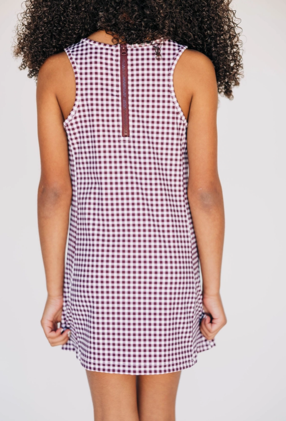 Person wearing a sleeveless checkered dress on a plain background