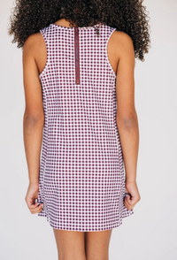 Person wearing a sleeveless checkered dress on a plain background