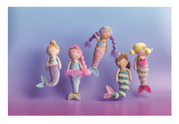 Four handmade mermaid dolls with soft pastel-colored yarn and striped tails, arranged on a purple and blue gradient background.