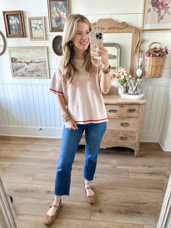 Woman taking a mirror selfie in a room with wooden flooring and decorative items.