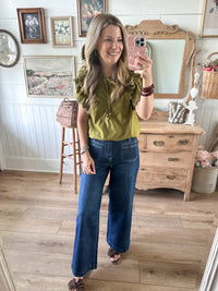 fall green blouse in home setting with crop wide leg denim jeans 
