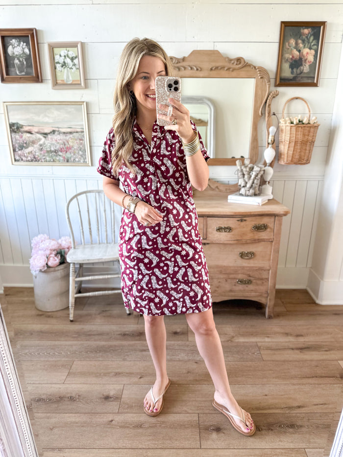 Woman taking a mirror selfie wearing a red floral dress in a home setting.