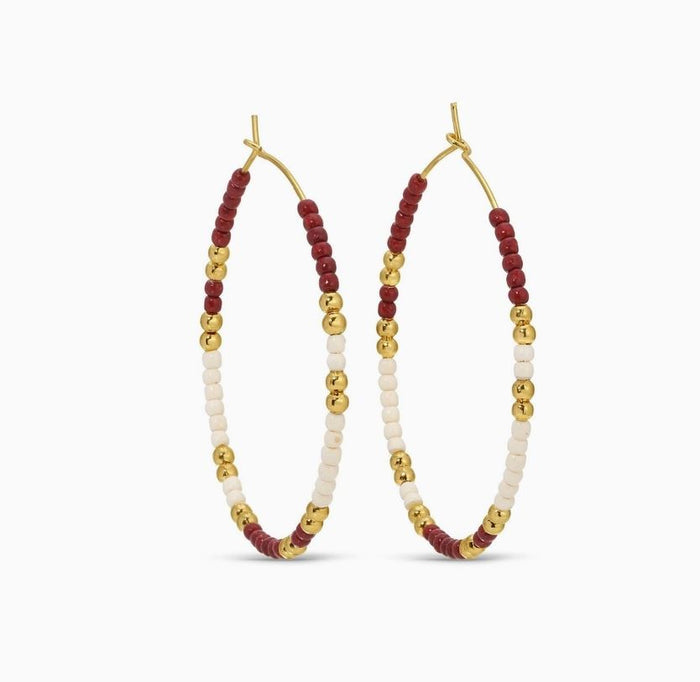 Hoop earrings with maroon, gold, and white beads on a white background