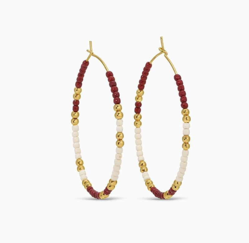 Hoop earrings with maroon, gold, and white beads on a white background