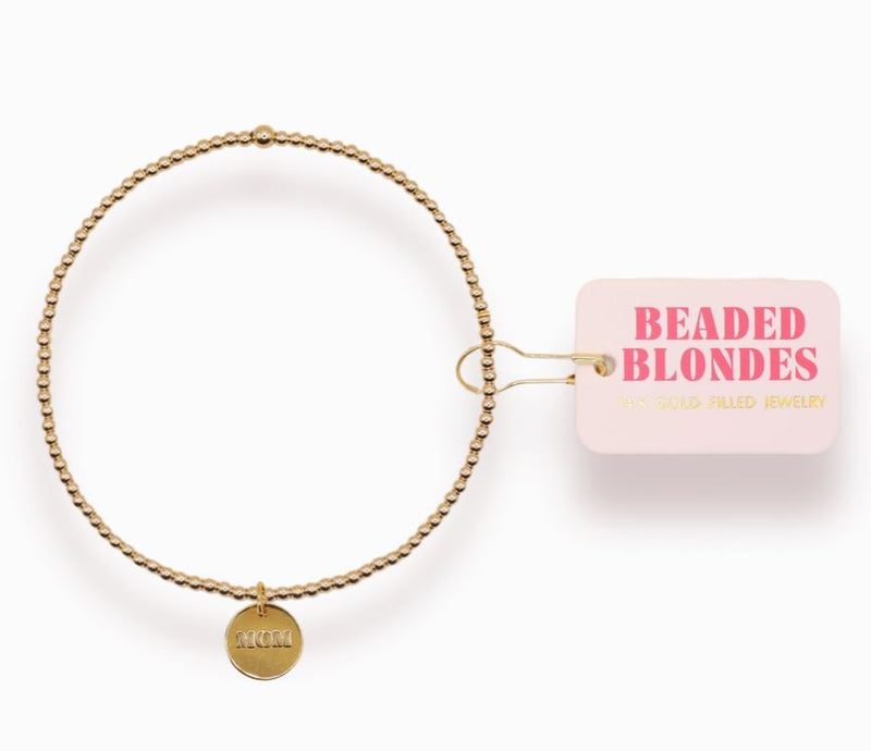 Gold beaded bracelet with a pink container labeled 'Beaded Blondes' on a white background