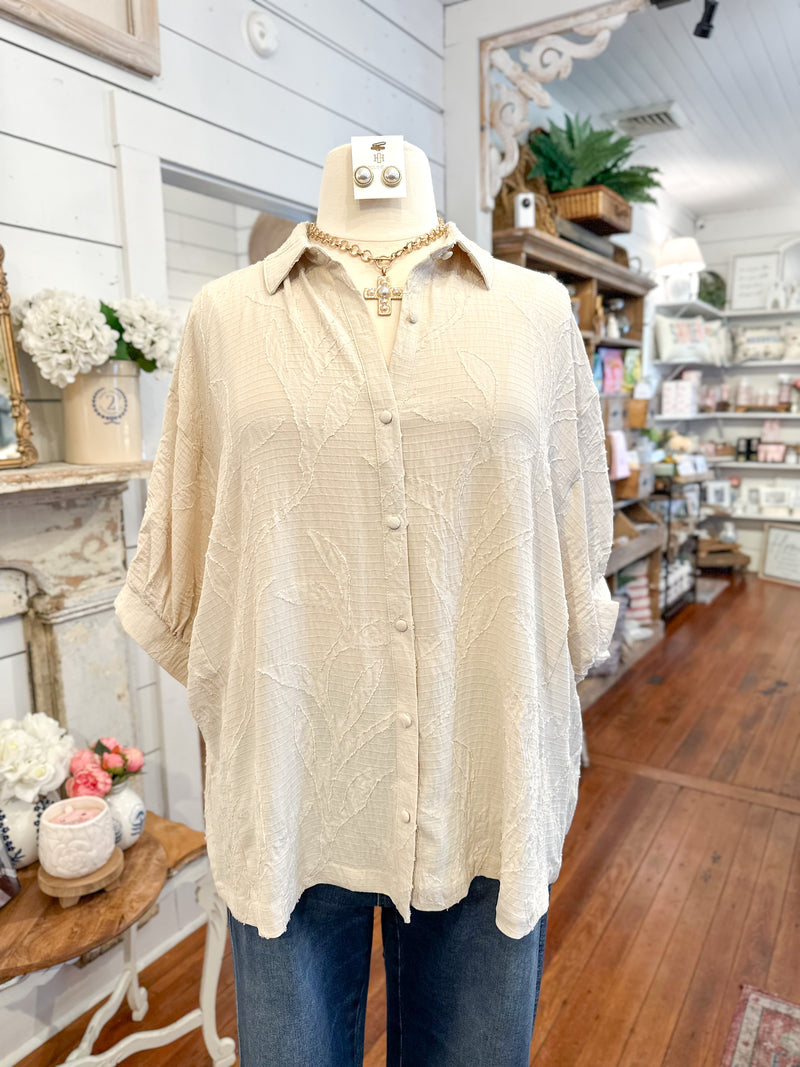 Mannequin wearing a cream floral button-up shirt and blue jeans in a store setting.
