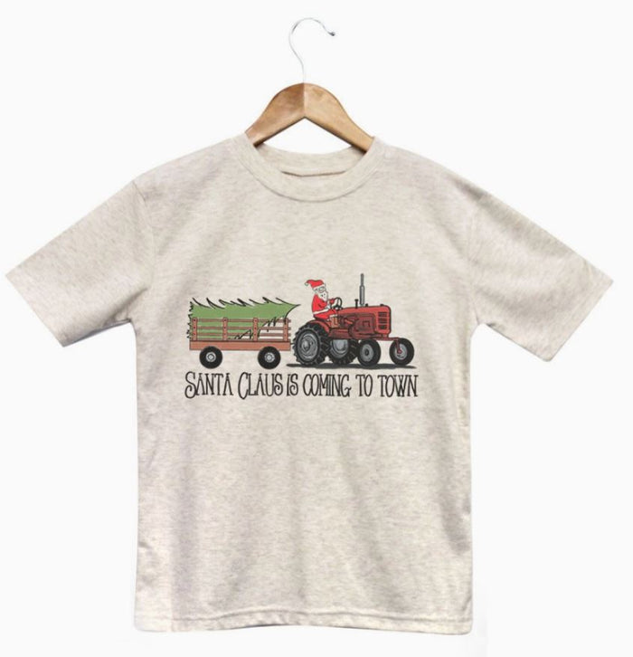 Children's t-shirt with a graphic of Santa Claus on a tractor and the text 'Santa Claus is Coming to Town' on a white background.