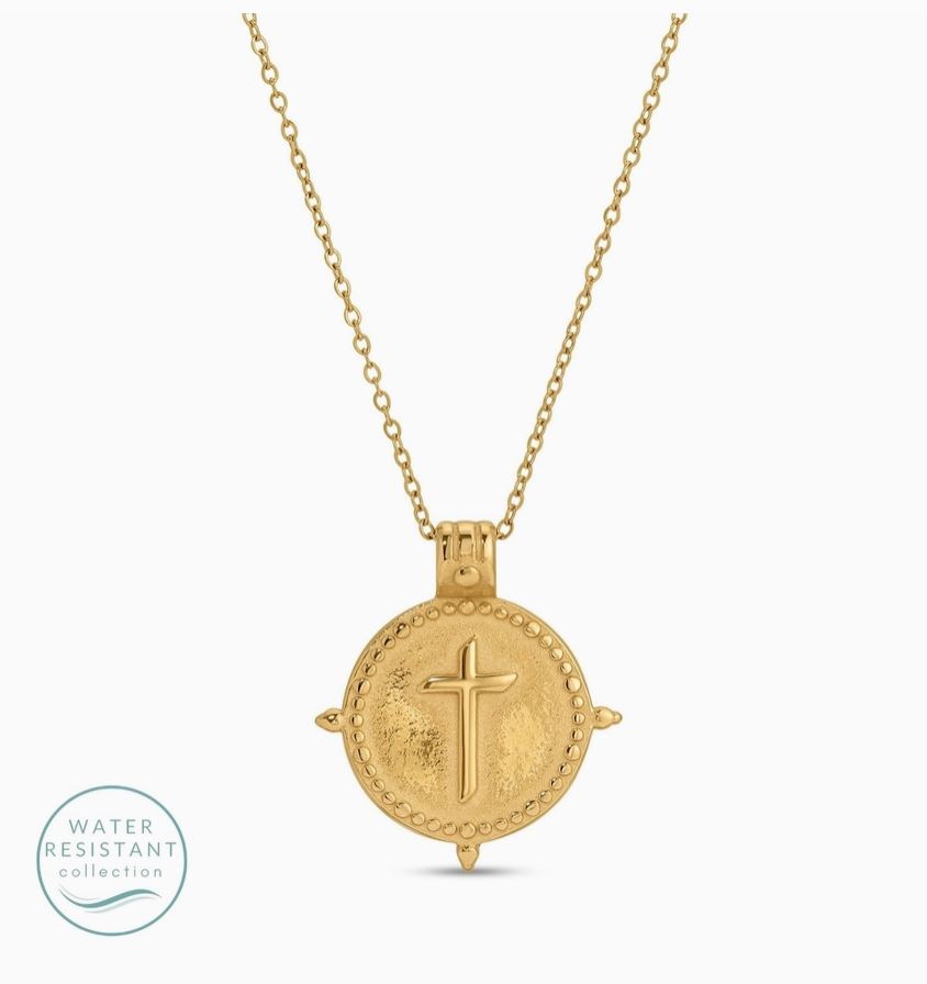 Gold necklace with a round pendant featuring a cross on a white background