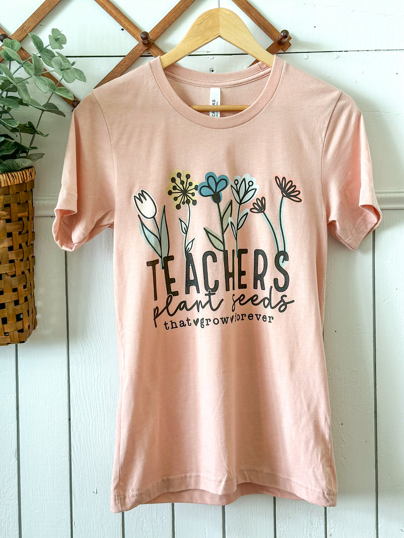 pink color tee that says teachers plant seeds that grow forever